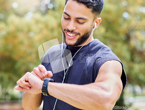 Image of Set the clock and just go for your goals. a sporty young man listening to music and checking his watch while exercising outdoors.