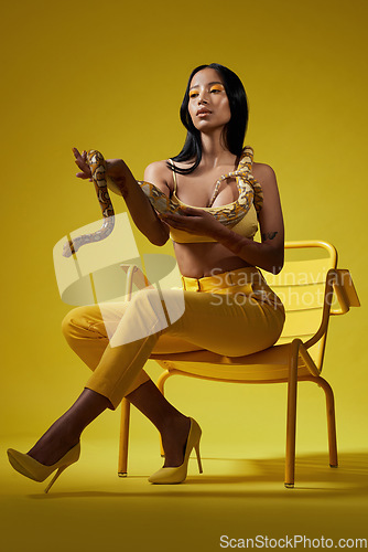 Image of Just follow the yellow. a fashionable woman holding a snake while modelling a yellow concept.