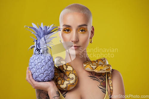 Image of Keep them distracted. Shot shot of a woman holding a painted pineapple while posing with a snake around her neck.