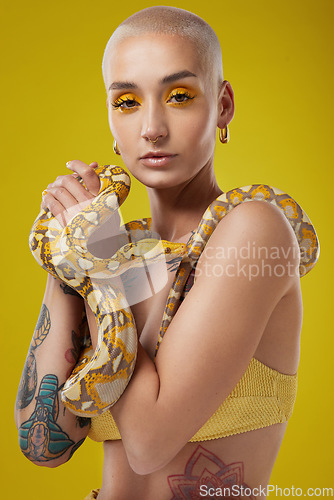 Image of Life is all about overcoming your fears. a fashionable woman holding a snake while modelling a yellow concept.