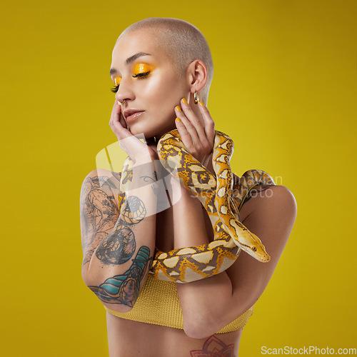 Image of I dream in shades of yellow. a fashionable woman holding a snake while modelling a yellow concept.