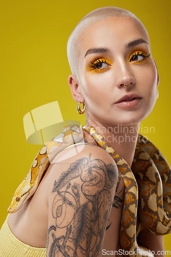 Image of They should be scared of me. a young woman posing with a snake around her neck against a yellow background.