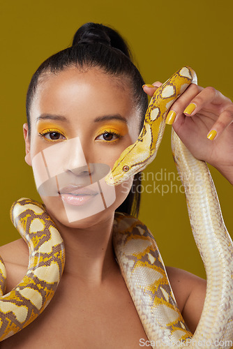 Image of I dont bark, I hiss. a young woman posing with a snake around her neck against a yellow background.