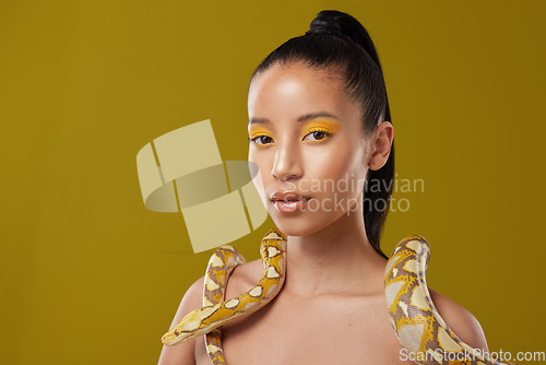 Image of You can trust me. a young woman posing with a snake around her neck against a yellow background.