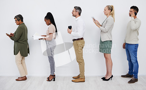 Image of Full length profile of diverse group of businesspeople standing in line together to wait while using technology and paperwork. Team of professionals queueing in row for an interview for a job vacancy