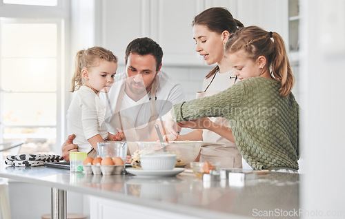 Image of Everyone gets a turn to whisk. a family baking together in the kitchen.