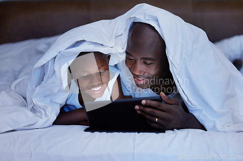 Image of The memories we make with our family is everything. a Father and son using a tablet in bed at night.