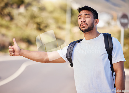 Image of Someone please stop for me. a young man hitchhiking on the side of the road.