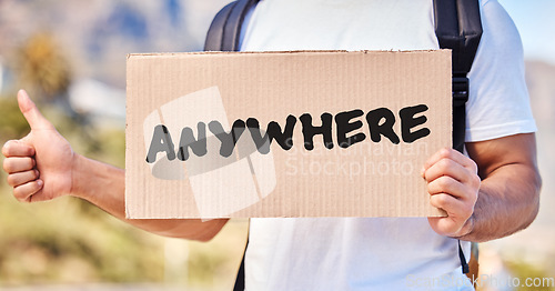 Image of I need to go someplace I know. Closeup shot of an unrecognisable man holding a sign that reads anywhere while hitchhiking on the side of the road.