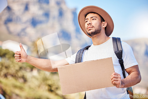 Image of Help me please. a young man holding a blank sign while hitchhiking on the side of the road.