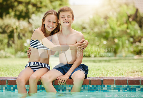 Image of We spend most of our day by the pool. a young boy and girl sitting with their feet in the pool.