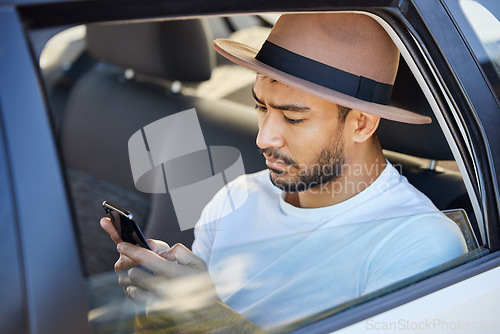 Image of If you’re on a road trip, you need driving music. a young man sitting in a car while using his phone.