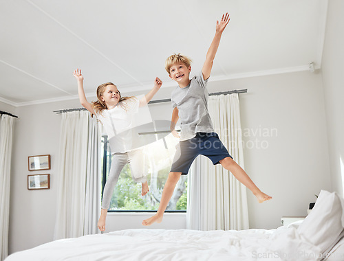 Image of The best influence. a brother and sister having fun while jumping on a bed together at home.