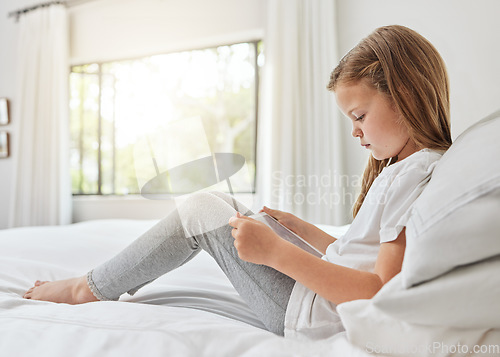 Image of Shes a bit of an introvert. a little girl using a digital tablet in bed at home.