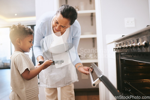 Image of These memories will last forever. a mature woman helping her grandchild safely open the oven at home.