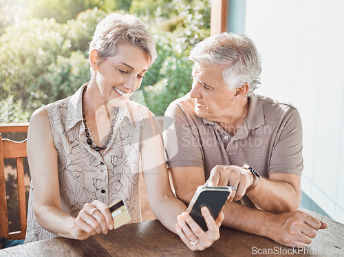 Image of So we get rewarded for shopping online. a mature couple sitting together while using a cellphone and a credit card.