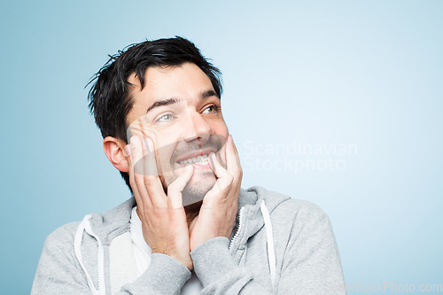 Image of Thinking of silly things. a young man touching his face against a studio background.