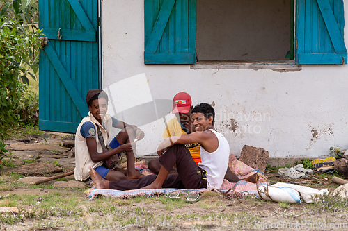 Image of Young Malagasy men resting in the shade of a house and playing cards. Andringitra, Madagascar