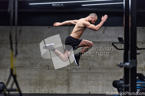 Image of A muscular man captured in air as he jumps in a modern gym, showcasing his athleticism, power, and determination through a highintensity fitness routine