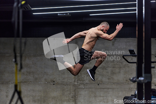 Image of A muscular man captured in air as he jumps in a modern gym, showcasing his athleticism, power, and determination through a highintensity fitness routine