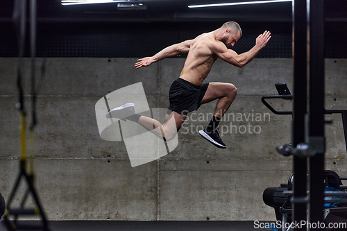 Image of A muscular man captured in air as he jumps in a modern gym, showcasing his athleticism, power, and determination through a highintensity fitness routine