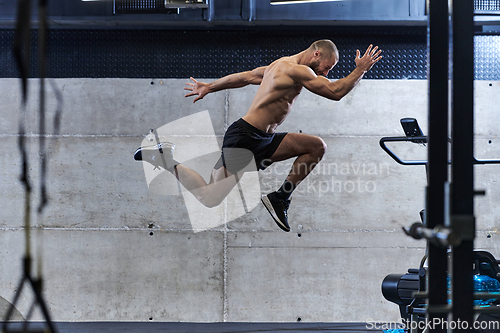 Image of A muscular man captured in air as he jumps in a modern gym, showcasing his athleticism, power, and determination through a highintensity fitness routine