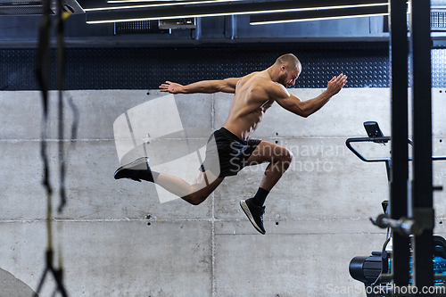 Image of A muscular man captured in air as he jumps in a modern gym, showcasing his athleticism, power, and determination through a highintensity fitness routine