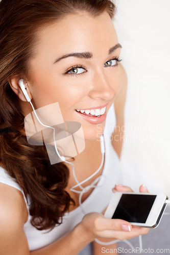 Image of Never too far from her phone. a young woman listening to music on her cellphone.