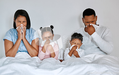 Image of Were all down. a family blowing their noses while sick at home.