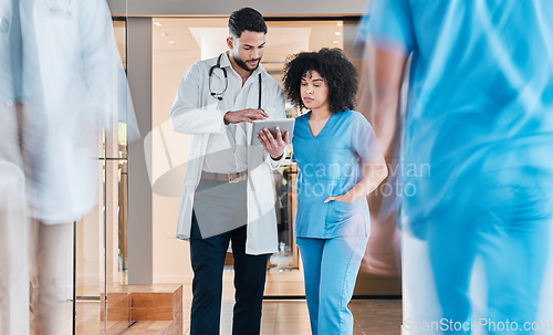 Image of Less paperwork means more time for patient care. two young doctors using a tablet and having a discussion in a modern office.