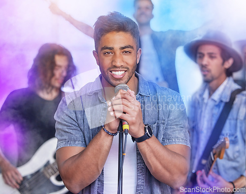 Image of Theyre a group of crowd pleasers. Cropped portrait of a handsome young male singer performing on stage with his bandmates in the background.