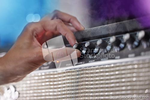 Image of Turn it up. an unrecognizable male performer adjusting his amp during a concert.