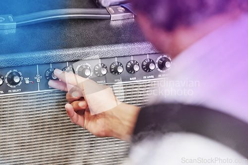 Image of Pump up the volume. an unrecognizable male performer adjusting his amp during a concert.