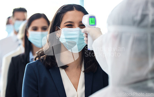 Image of Making sure youre good to go. a group of businesspeople standing in a line to get their temperatures read.