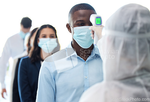 Image of Lets check your temperature. a group of businesspeople standing in a line to get their temperatures read.