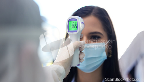 Image of Ensuring everyone is safe. a group of businesspeople standing in a line to get their temperatures read.