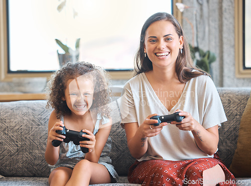 Image of Hispanic mother and daughter battling while playing video games together while sitting on the couch at home. Fun young mother and daughter using joysticks while playing and spending free time togethe