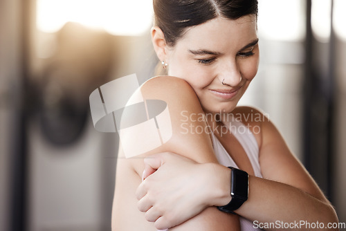 Image of Caucasian athlete suffering from arm injury during workout in gym. Strong, fit, active woman standing alone and touching while feeling pain in training and exercise at health club. Cramp in muscle