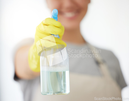 Image of One unrecognizable woman holding a cleaning product while cleaning her apartment. An unknown domestic cleaner wearing latex cleaning gloves