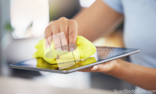 Image of An unrecognizable woman cleaning her digital tablet in her apartment. One unknown woman using a rag to remove dust from her device