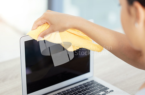Image of An unrecognizable woman cleaning her laptop in her apartment. One unknown woman using a rag to remove dust from her laptop keyboard