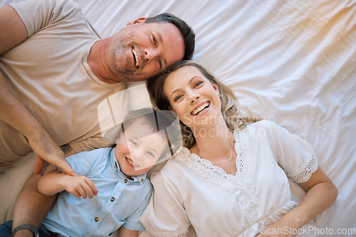 Image of Portrait of a happy caucasian family lying on the bed relaxing from above. Two parents bonding with their son at home. Smiling young family being affectionate with their child resting on their bed.