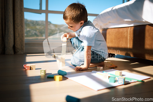 Image of Little boy building a tower with wooden blocks. Adorable caucasian child stacking toys while developing fine motor skills and hand-eye coordination. Boy playing with building blocks or wooden cubes