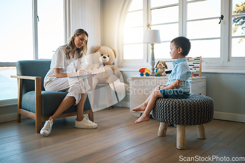 Image of An adorable little boy sitting on a chair while talking to a caucasian therapist. Cute little boy talking to a psychologist. Child checking in with a counsellor at a foster home before being adopted