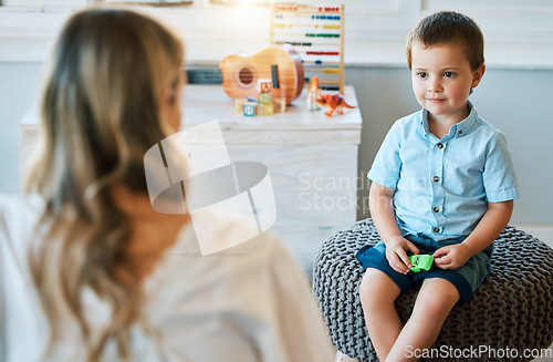 Image of An adorable little boy sitting in his bedroom at home and talking to his mother. Happy male child bonding with his mom. Rearview of a blonde woman spending quality time with her young son on a weeken