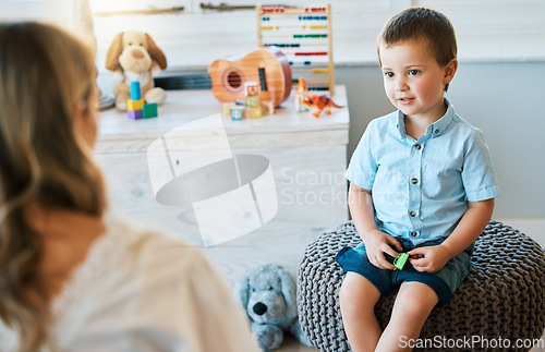 Image of An adorable little boy sitting on a chair while talking to a caucasian therapist. Cute little boy talking to a psychologist. Child checking in with a counsellor at a foster home before being adopted