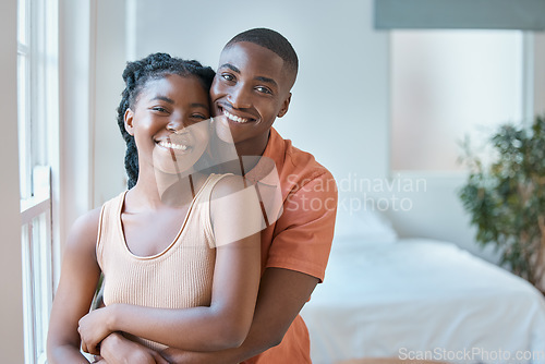 Image of Portrait of a young black african american couple smiling as they lovingly embrace in the bedroom at home. An affectionate good looking black man and woman spending time together and looking in love