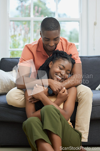 Image of Young african american couple hugging at home, relaxing in the lounge on the couch. Content young couple bonding, embracing affectionately at home. Married couple on romantic date at home being cosy