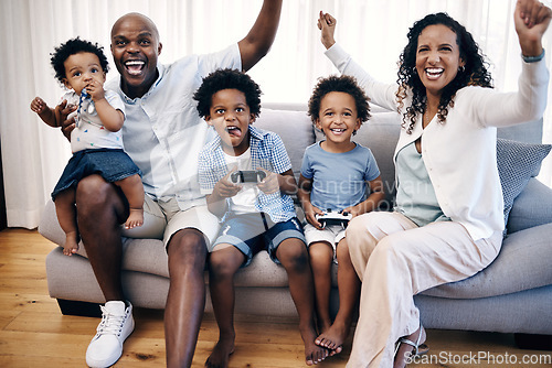 Image of Two little boys playing video games while sitting with their family. African american family of five having fun and spending time together. Mom and dad cheering as sons win