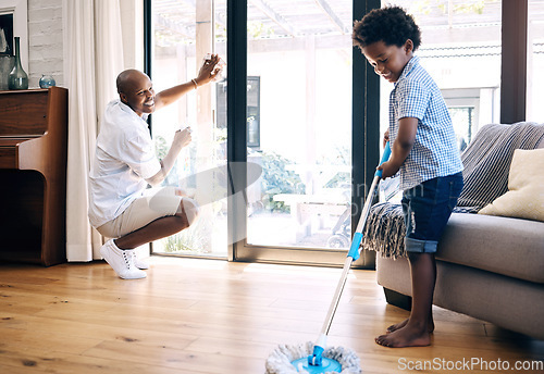 Image of Mature african american dad and his young little son doing housework in the lounge at home. Black man and his boy having fun while cleaning their home together. Black boy and his dad cleaning